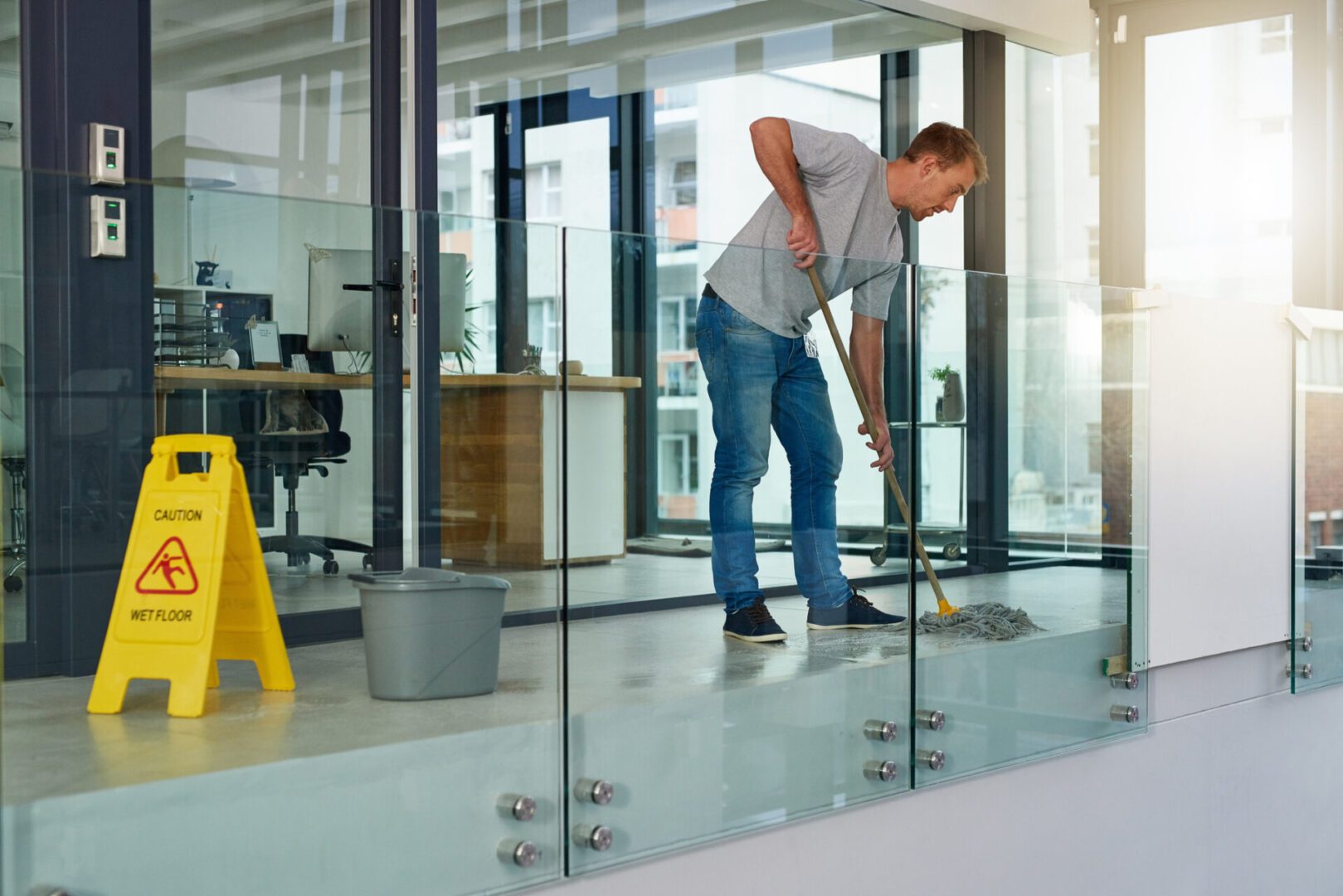 A man sweeping the floor in an office building.