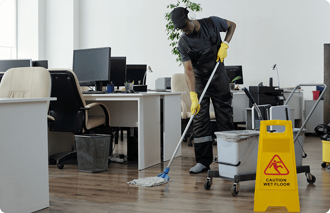 A man in black shirt and yellow gloves cleaning floor.