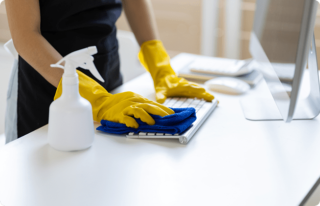 A person in yellow gloves cleaning a computer keyboard.