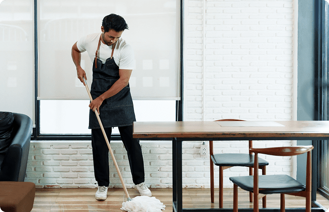 A man in an apron is mopping the floor